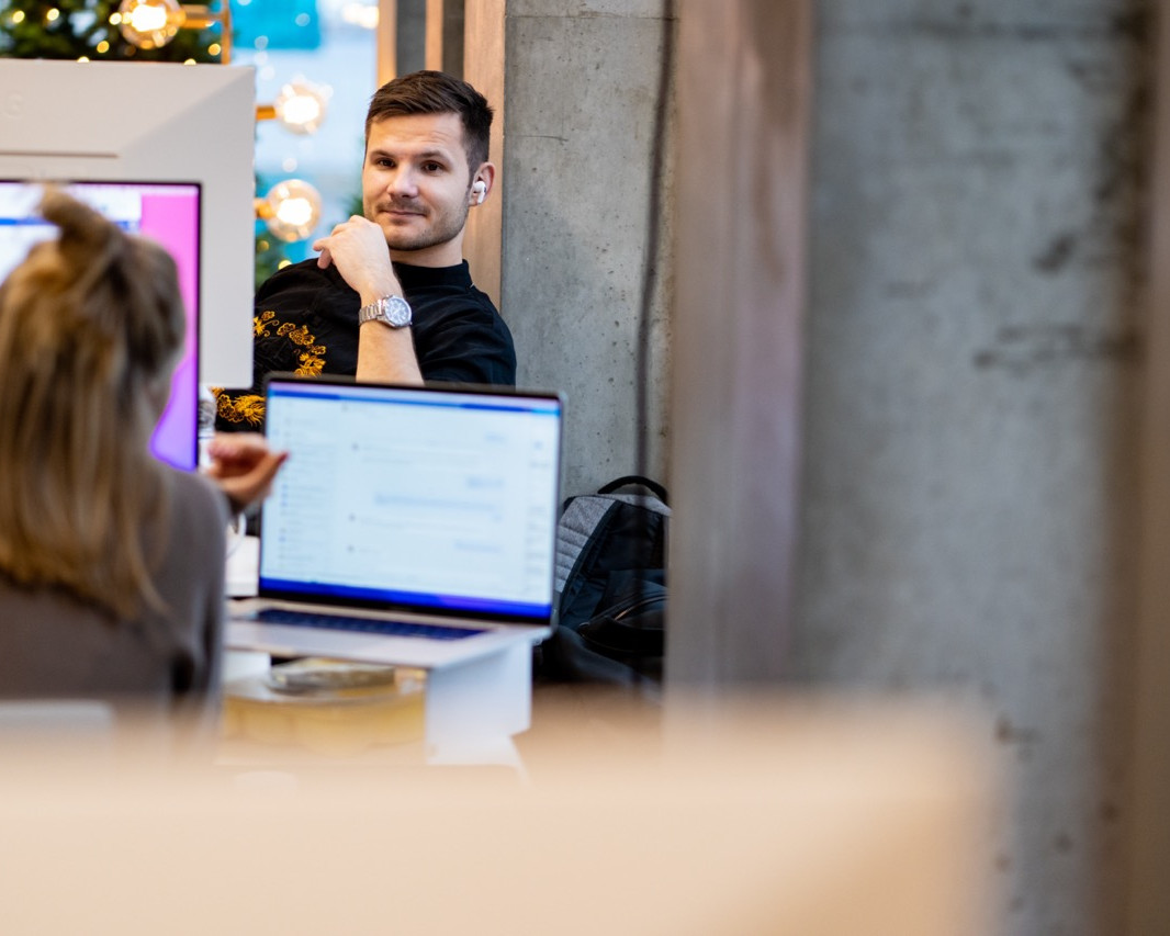 En mand og en kvinde arbejder sammen ved computere i et moderne kontormiljø